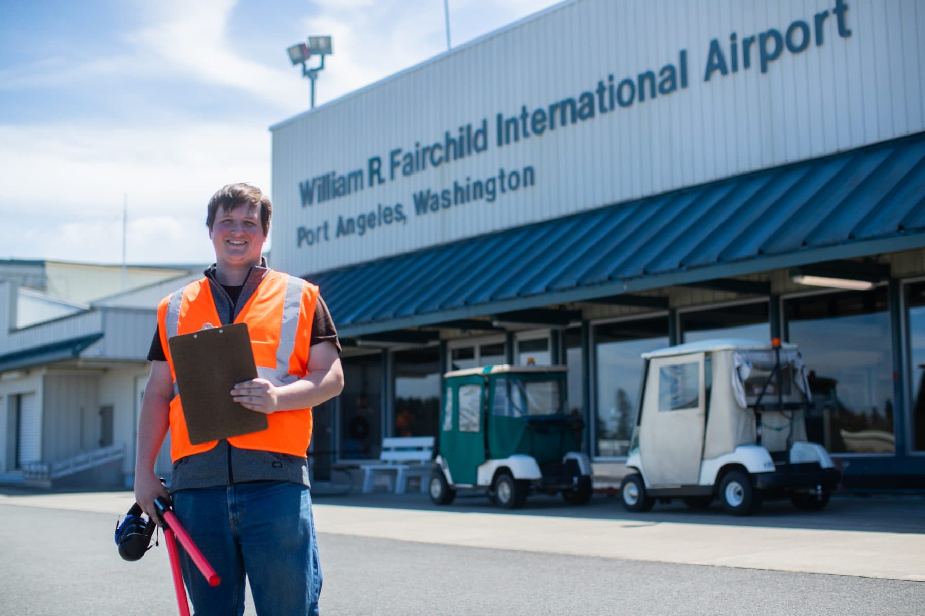A Citizen Air line technician in an orange vest talking with a pilot on the ramp, a Cirrus SR22 behind them