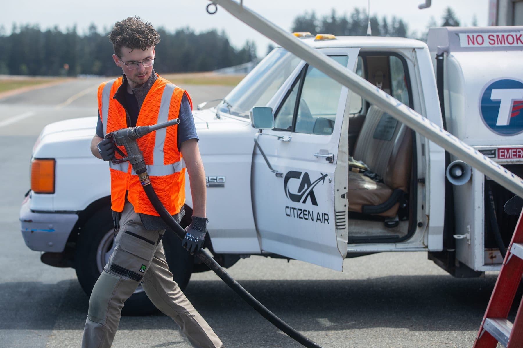 A Citizen Air line technician walking the fuel hose from the Citizen Air fuel truck on the ramp