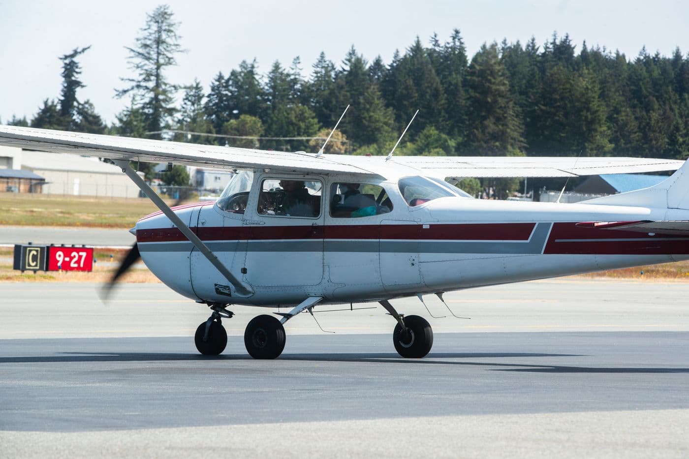 A Citizen Air Cessna 172 taxiing past the Runway 9-27 sign