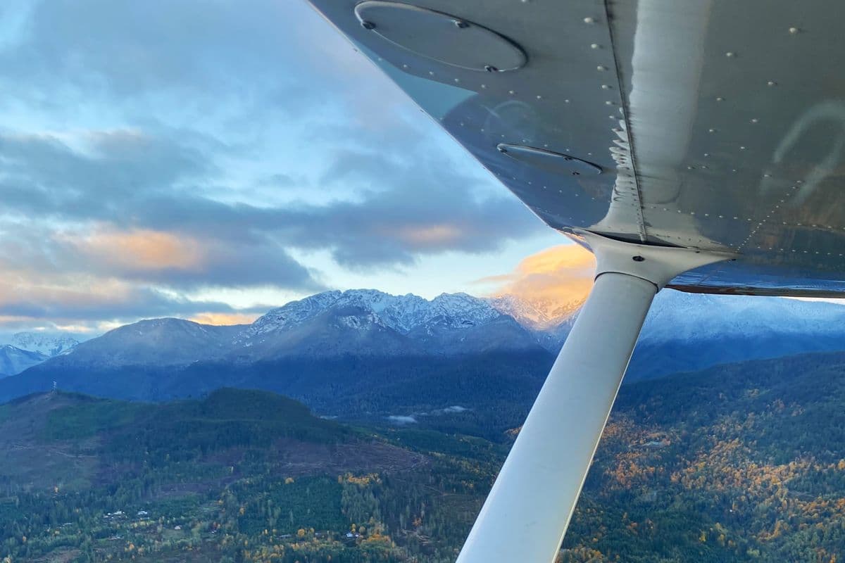 The snow-covered Olympic Mountains at sunset from the cabin of a Citizen Air aircraft