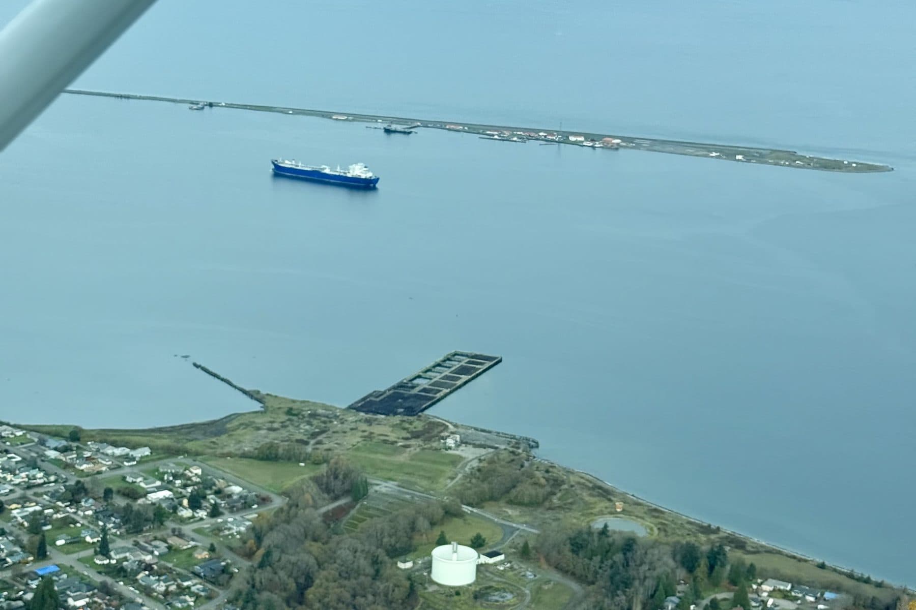 Ediz Hook and a ship in the harbor beyond the wing strut of a Citizen Air Cessna